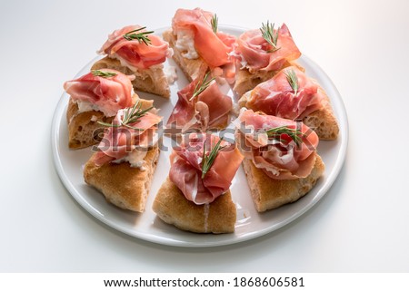 gourmet focaccia with prosciutto of Parma ham, mozzarella and rosemary sprigs, eight tasty slices of pizza on a white plate Royalty-Free Stock Photo #1868606581