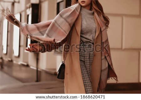 Young woman with cropped head in the grey knitted cozy sweater and brown coat walking on the street. Outdoor portrait in daylight. Warm winter clothes concept Royalty-Free Stock Photo #1868620471