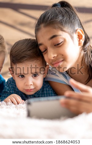 friendship, childhood, technology concepts - 2 young children baby of different nationalities Persian and Slavic appearance watch cartoon on smartphone on bed. kids preschool speak by video conference