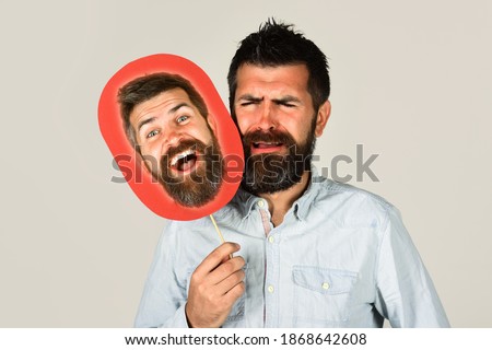 Advertising. Face expression. Emotions. Bearded man holds board with face. Feeling and emotions. Face expression. Man choose emotion mask. Psychology.