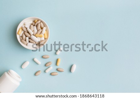 Pills, capsules, vitamins and natural organic food supplements on white plate on light blue background. Minimal modern pharmacy or health care concept. Flat lay, top view, copy space Royalty-Free Stock Photo #1868643118