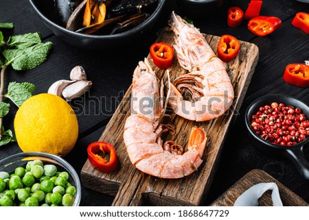 Tiger shrimps on cutting board on black wooden surface