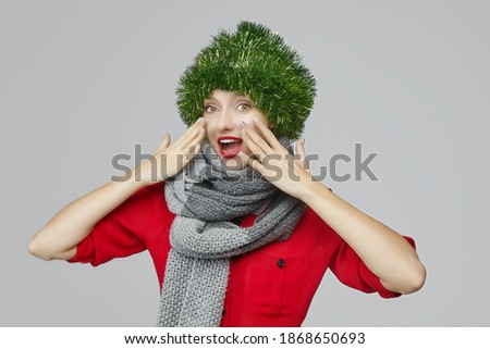 attractive girl with a Christmas decoration on her head, holding her hands to her face in surprise. photo session in the Studio on a white background