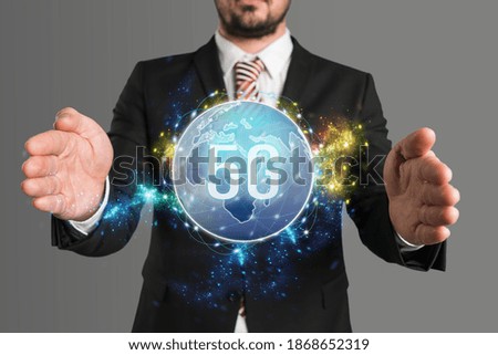 businessman presenting a virtual world map with message 5G in front of grey background