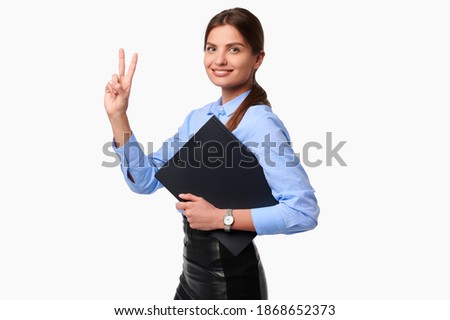 Businesswoman holding folder on white isolate background. Smiling caucasian female worker in uniform showing victory gesture