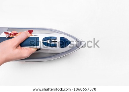 Girl's hand ironing a white tablecloth background, top view