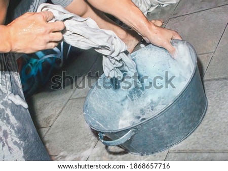 Man's hands washing clothes in an iron basin, close-up