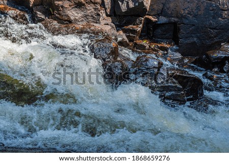 Close up of river rapids showing running water through river rocks on a sunny summer day