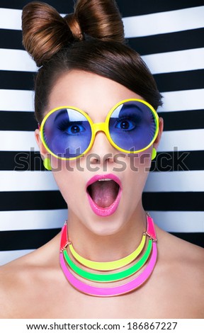 Attractive surprised young woman wearing sunglasses on striped background, beauty and fashion concept 