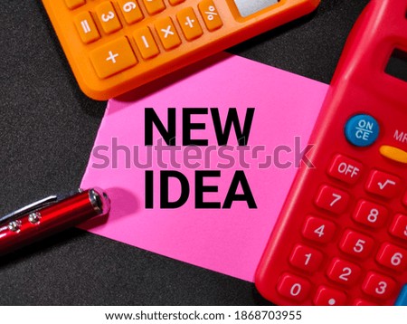 Selective focus.NEW IDEA in black word on pink paper with calculator and pen with black background.Business concept.