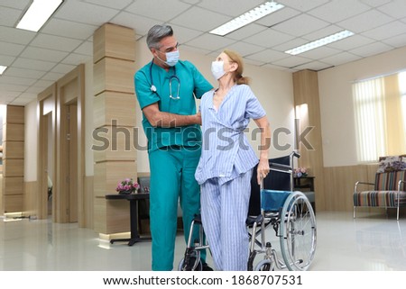 Doctor or assistance staff help or assist an elder patient woman while try to standing after sit on wheelchair in the hospital
