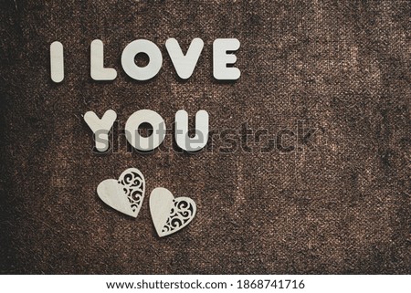 I love you concept on bronze sackcloth. Two wooden hearts and letters. Postcard design template for birthday, mother's day, valentine's day and other holidays and events. Place for text.