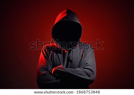 Silhouette af man without face in hood on a red background. Anonymous crime concept Royalty-Free Stock Photo #1868753848