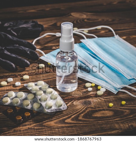 Medical masks, pills, antiseptic in a transparent plastic bottle and black rubber gloves on a wooden background. Covid-19 virus protection medical concept. Studio photo with vignetting.