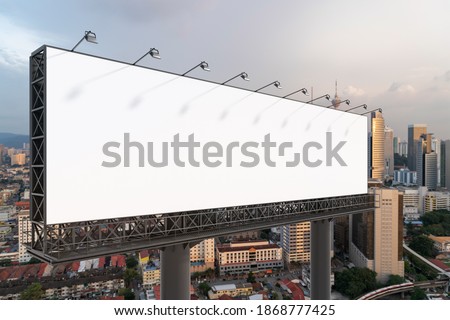 Blank white road billboard with Kuala Lumpur cityscape background at sunset. Street advertising poster, mock up, 3D rendering. Side view. The concept of marketing communication