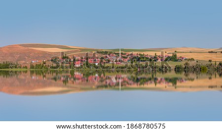 Rural Landscape with lake - A village with crop fields in Anatolia in the background a mosque with a white minaret