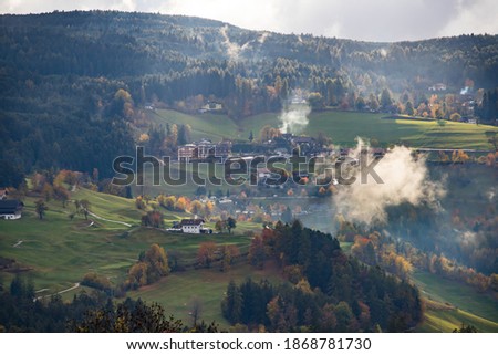 Small village in the autumn in Dolomite mountainsa surrounded by mist.