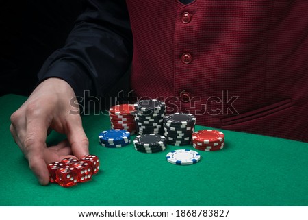 the croupier picks up the winning chips from the green poker table