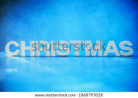 Word Christmas made of white concrete letters on neon light background. Copy space for your creative design. Festive invitation, greeting card.