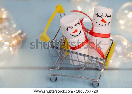 decorative marshmallow snowmen ride in a food cart on a lighted turquoise background close up