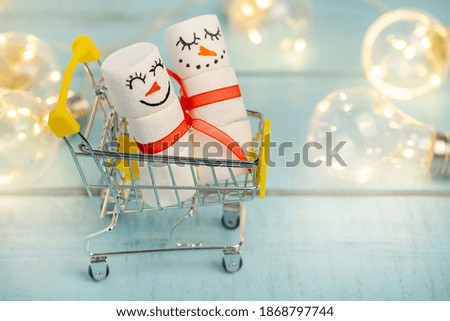 decorative marshmallow snowmen ride in a food cart on a lighted turquoise background close up