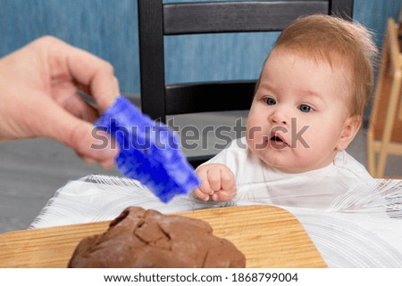 Mother shows a small child a cookie cutter. Close-up portrait of the baby. The concept of home cooking and cooking together with children
