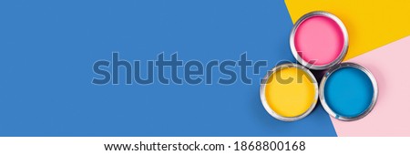 Blue, yellow, pink background with three colors paint cans. Flat lay, top view, copy space. Royalty-Free Stock Photo #1868800168