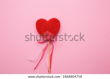 Closeup of a heart with a decor on a stick on a pink isolated background. Spell love in white letters.