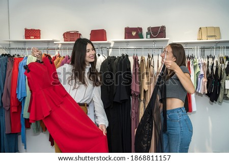 Two women in fashion boutique choose dress. Season holiday discounts for shopping. Black friday