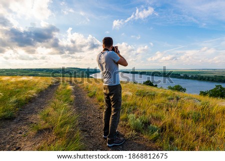 Back view of a photographer taking pictures of river landscape