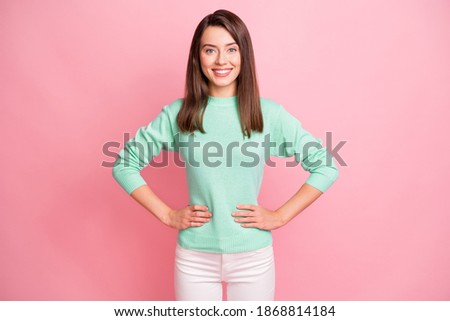 Portrait of charming content cheerful brown-haired girl hand on hips isolated over pink pastel color background
