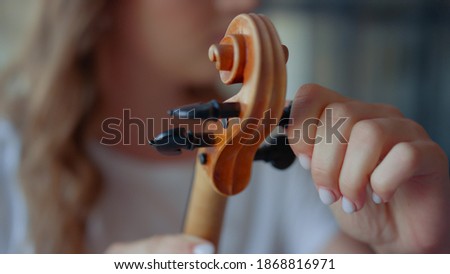 Teenage girl hands tuning violin. Young woman checking pegs of violin. Closeup female violinist tuning musical instrument. Lady holding string instrument in hands Royalty-Free Stock Photo #1868816971