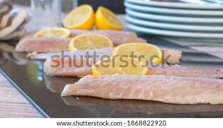 Redfish fillet fresh, raw and uncooked on a cutting board with sliced lemon. Closeup