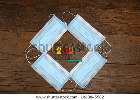 Medical mask and numbers 2021 on wooden background