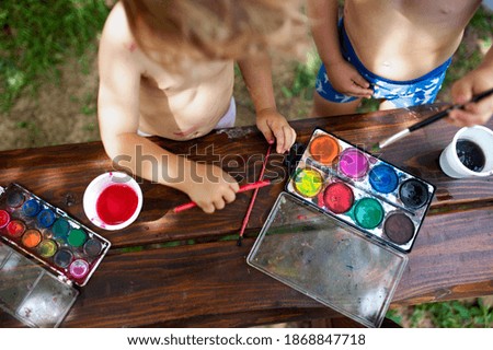 Unrecognizable boy and girl painting outdoors in summer.
