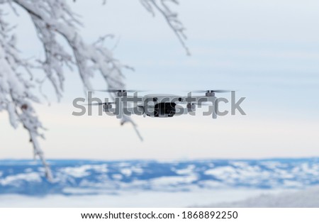 Flying mini drone in action on the winter snow landscape background. Image with selective focus on drone toning and noise