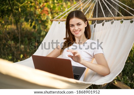 woman lies in hammock with laptop leisure communication technology outdoors