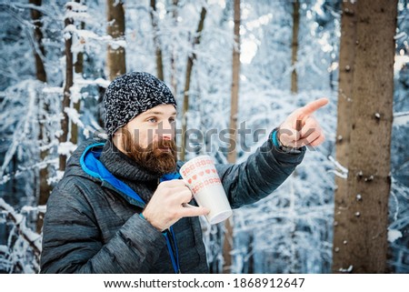 man drinking hot tea in winter forest