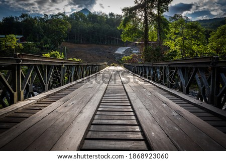 Wooden bridge with steel bar across the river