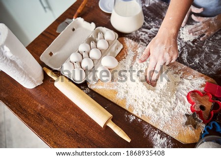 Cropped photo of a cook touching pile of flour on wooden kitchen table with all the tools for baking