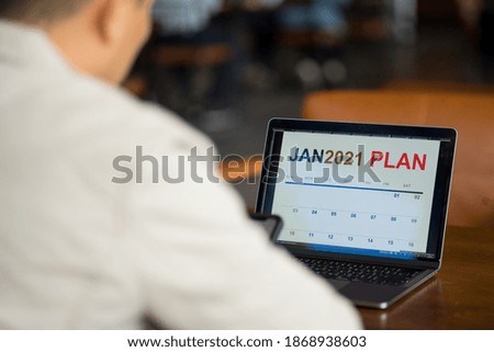 Close up of a businessman looking at new year 2021 planner on laptop screen to plan his business for coming new year.