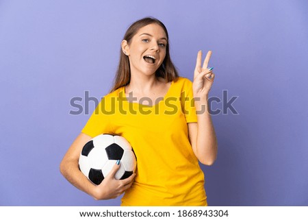 Young Lithuanian football player woman isolated on purple background smiling and showing victory sign