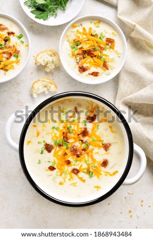 Creamy potato soup with bacon and cheddar cheese on light stone background. Healthy diet dish for dinner. Top view, flat lay