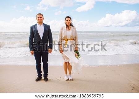 Happy just married middle age couple walk at beach and have fun on summer day.