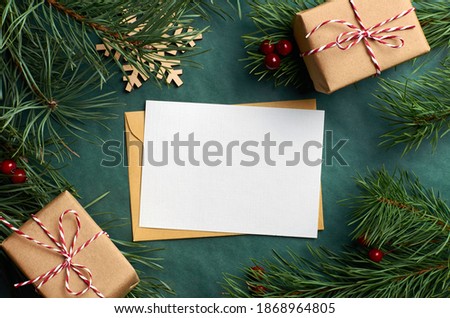 Christmas greeting card mockup with gift boxes and pine tree branches on green background