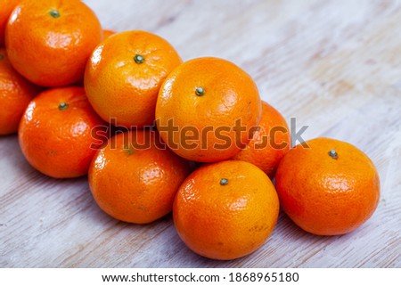 Pile of whole ripe organic clementines on wooden background..