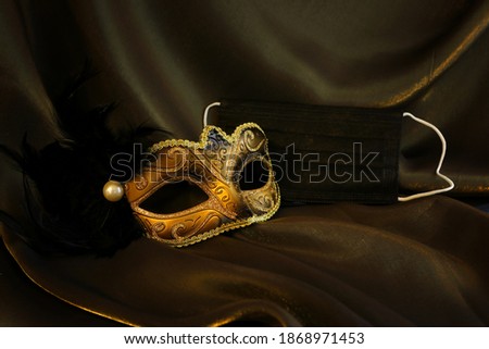 Photo of elegant and delicate gold Venetian mask over black silk background. Coronavirus prevention concept