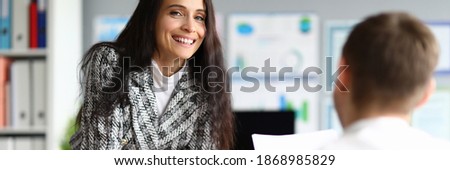 Portrait of pretty smart businesswoman posing on camera and signing contract. Smiling female in presentable costume in company office. Finance and economy concept