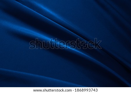Black dark navy blue elegant abstract background for design. Silk satin fabric with nice folds. Beautiful background with wavy lines. Copy space.                           