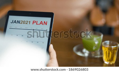 Close up of a businessman looking at new year 2021 planner on tablet screen to plan his business for coming new year.